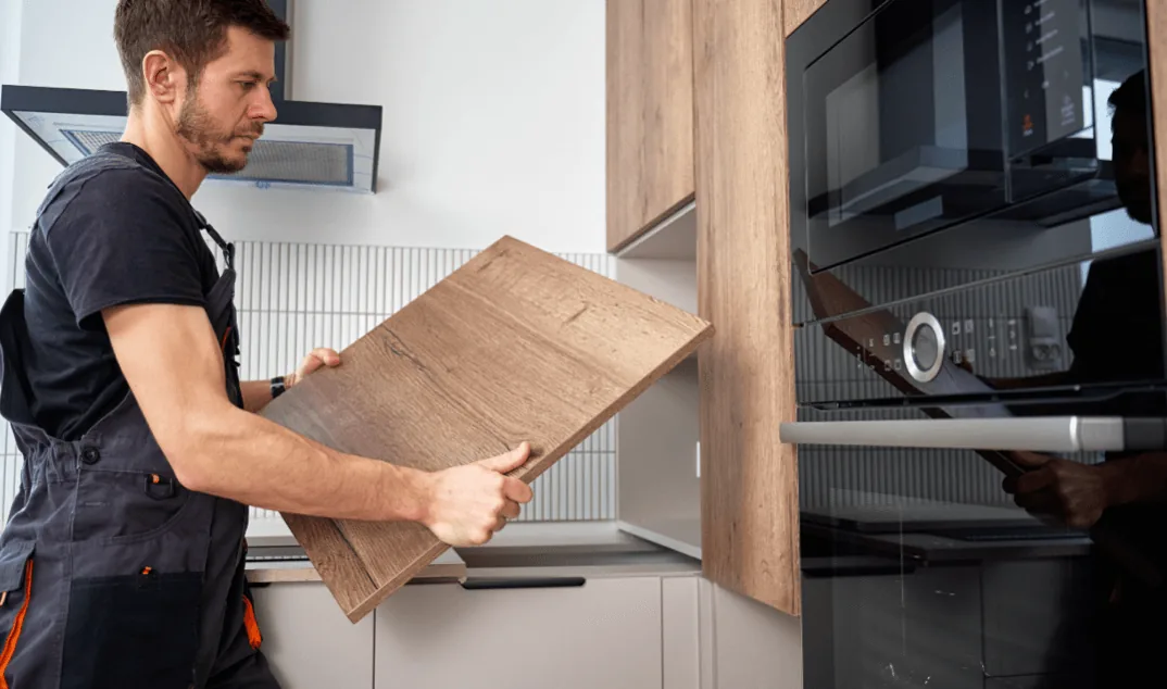Installateur Cuisines ELITE en train de poser une façade de meuble dans une cuisine sur mesure lors de l’installation, garantissant une finition précise et professionnelle.