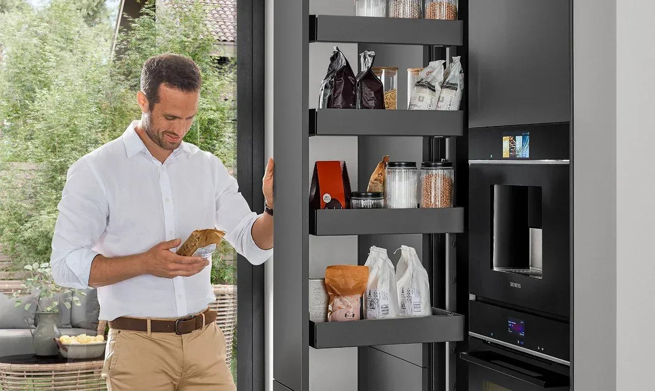 Homme consultant une colonne de rangement optimisée à tablettes coulissantes remplies de provisions
