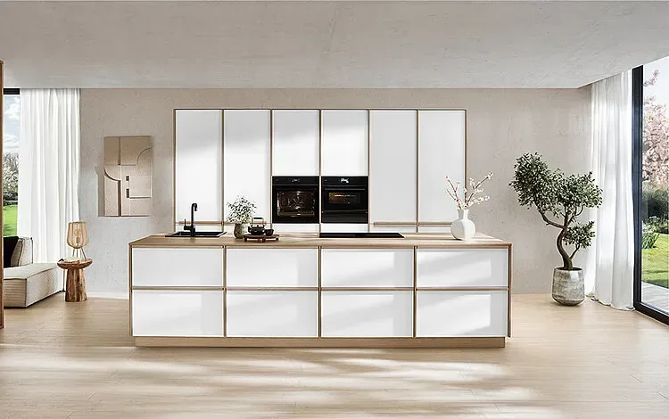 Cuisine design blanche avec îlot, plan de travail en bois et finitions laiton