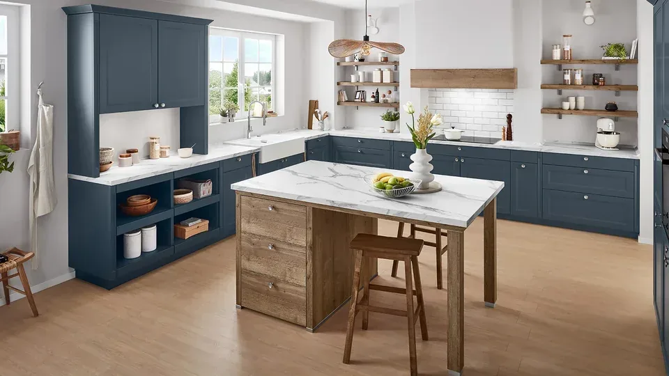 Cuisine en L bleu marine avec îlot central bois et plan de travail en marbre blanc