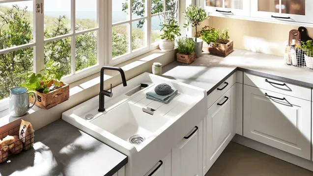 Cuisine en L style cottage blanc avec évier en céramique et vue sur jardin