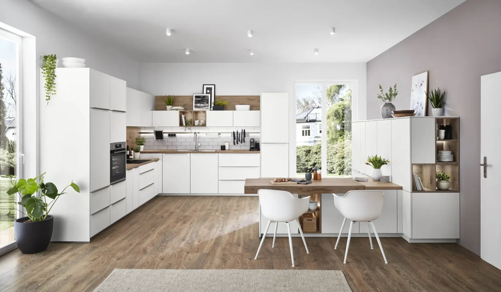 Cuisine équipée blanche en U avec rangements, niche bois et table intégrée