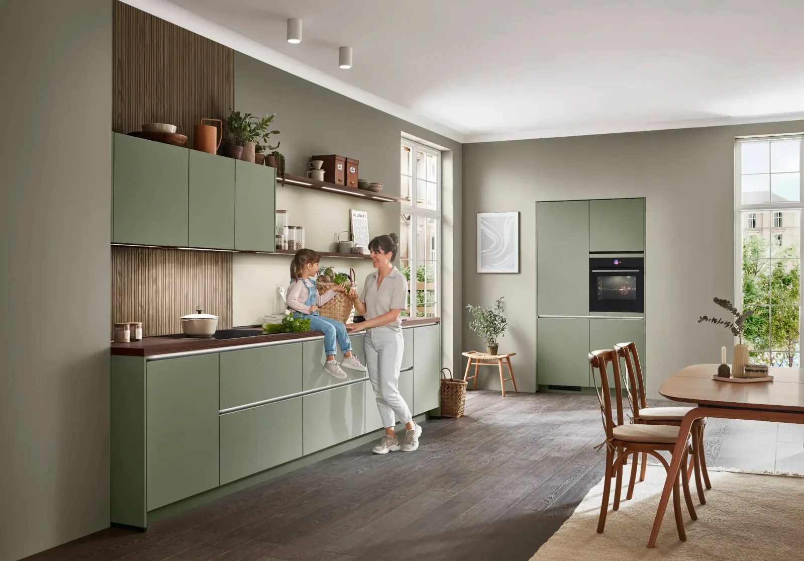 Cuisine équipée design vert sauge avec plan effet bois et coin repas attenant