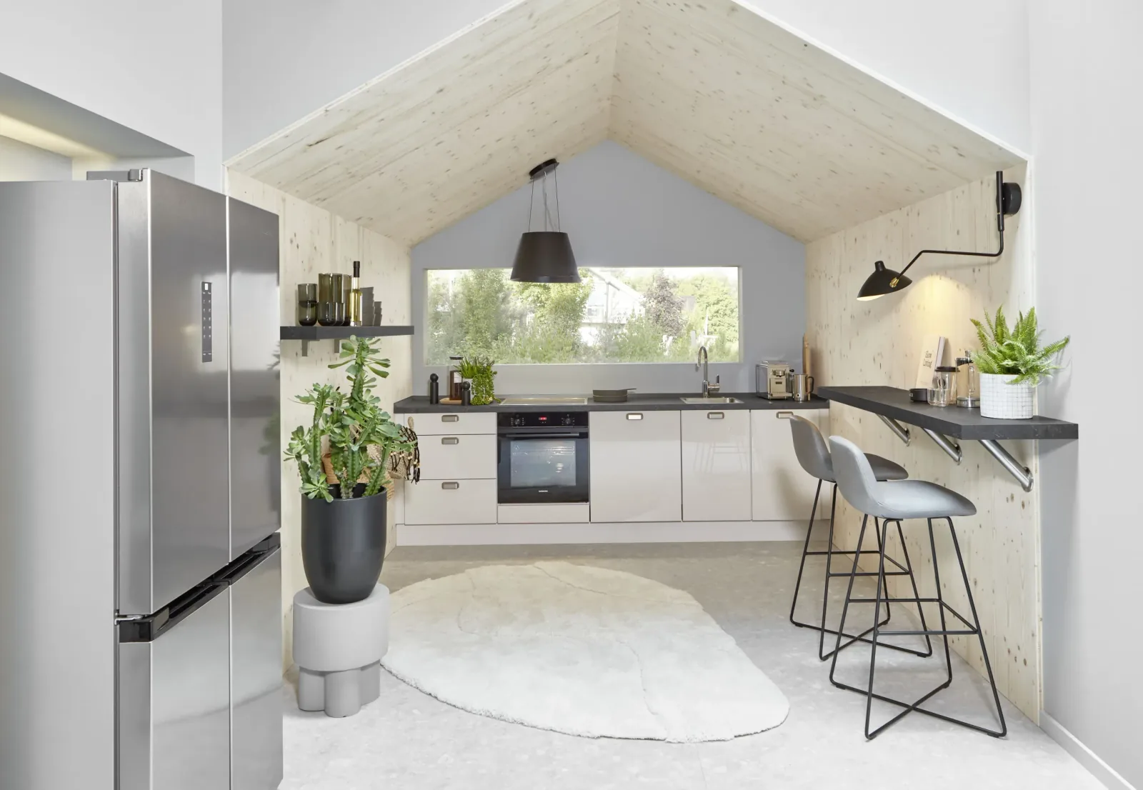 Cuisine équipée ouverte sous toiture bois avec bar et tabourets hauts