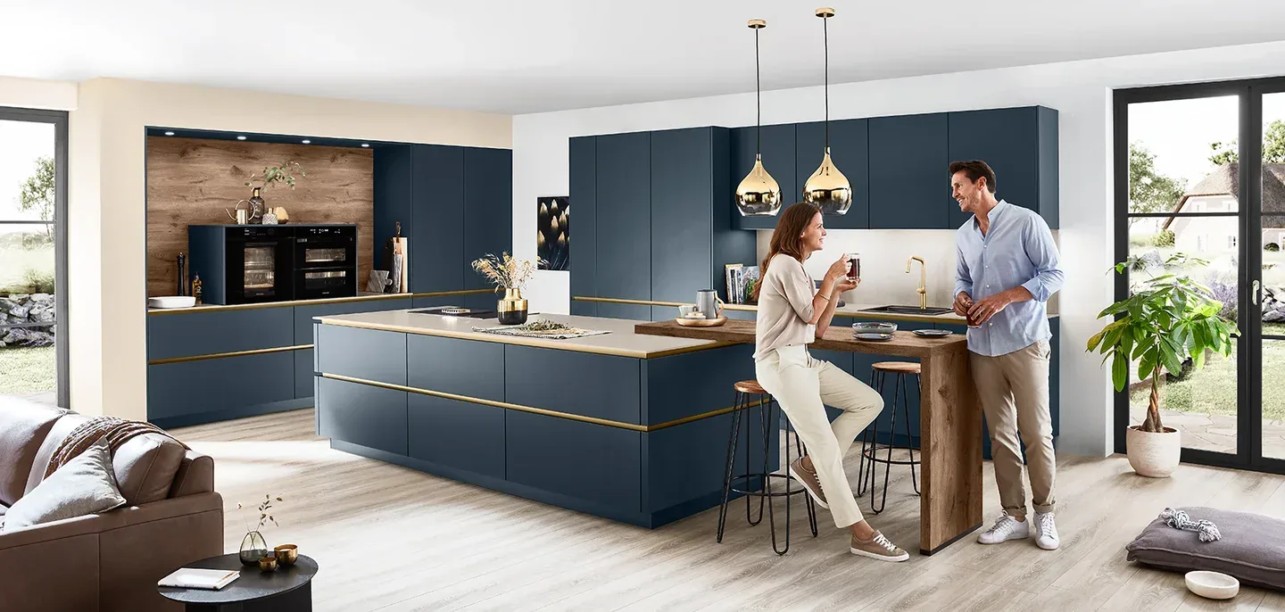 Cuisine ouverte design Line-N sans poignée bleu marine et laiton avec couple à l’îlot central