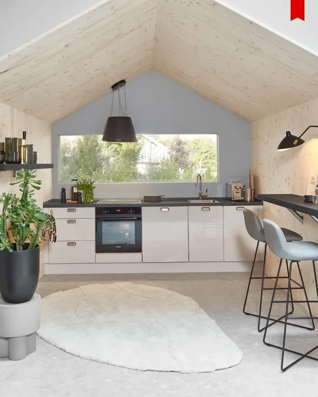 Cuisine linéaire beige sous toiture en bois avec suspension noire et coin bureau