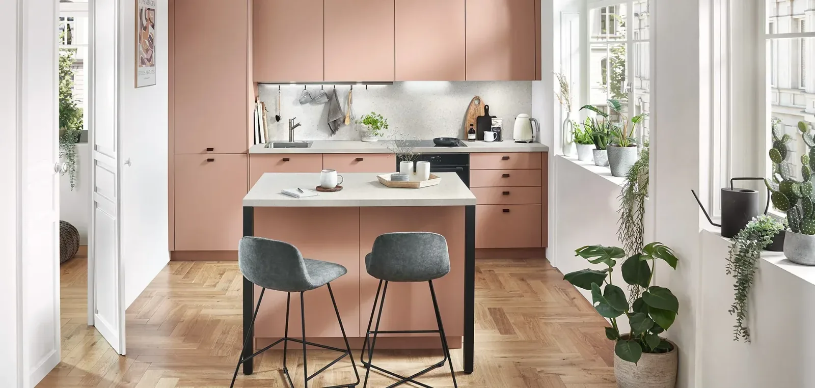 Cuisine linéaire rose poudré avec îlot central et chaises hautes grises