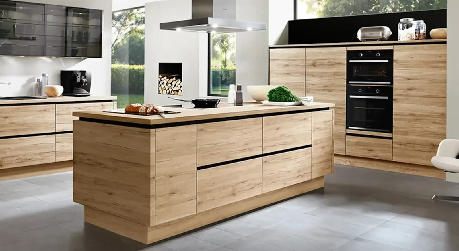 Cuisine ouverte matériau bois clair avec îlot central et plaque de cuisson intégrée