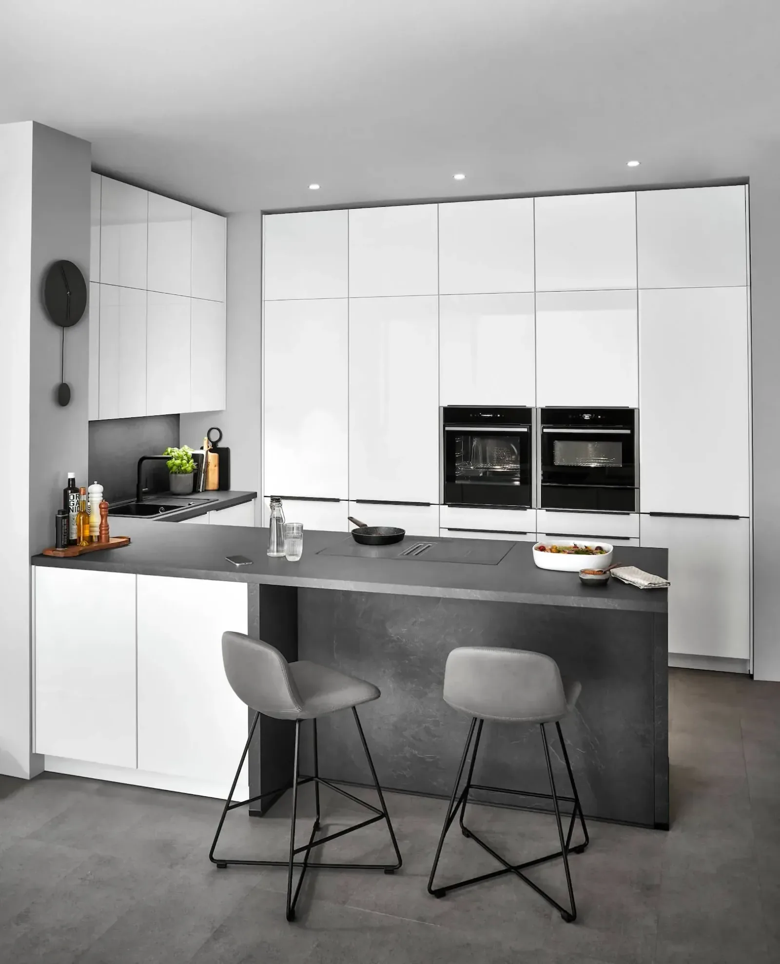 Cuisine optimisée blanche laquée avec îlot central noir, fours doubles et chaises hautes