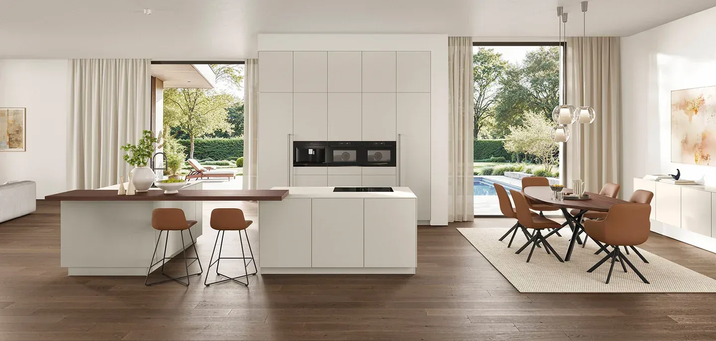 Cuisine ouverte minimaliste blanche avec îlot central et espace de vie donnant sur le jardin