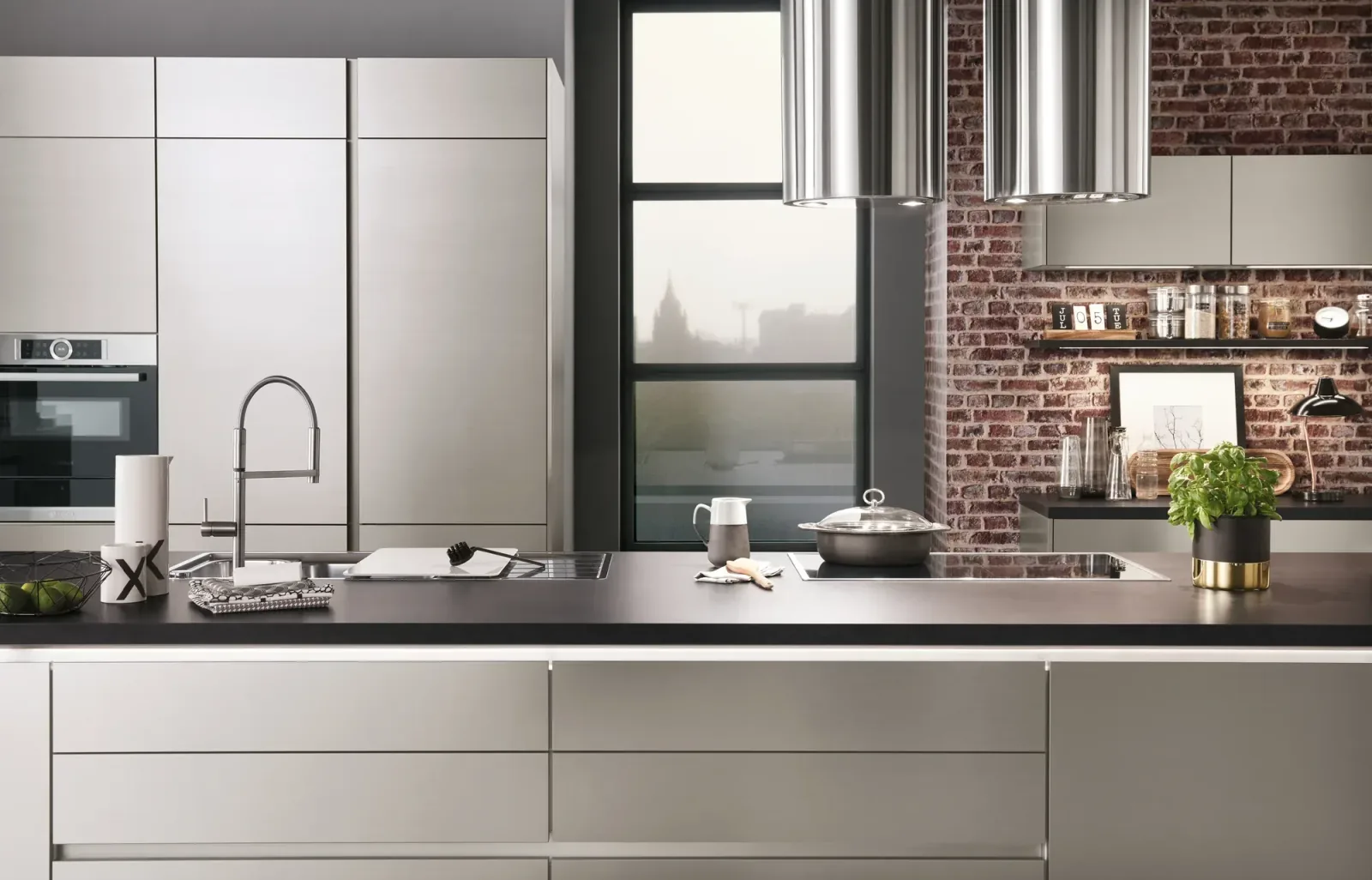 Cuisine style loft avec façades inox, hottes cylindriques et mur en briques apparentes