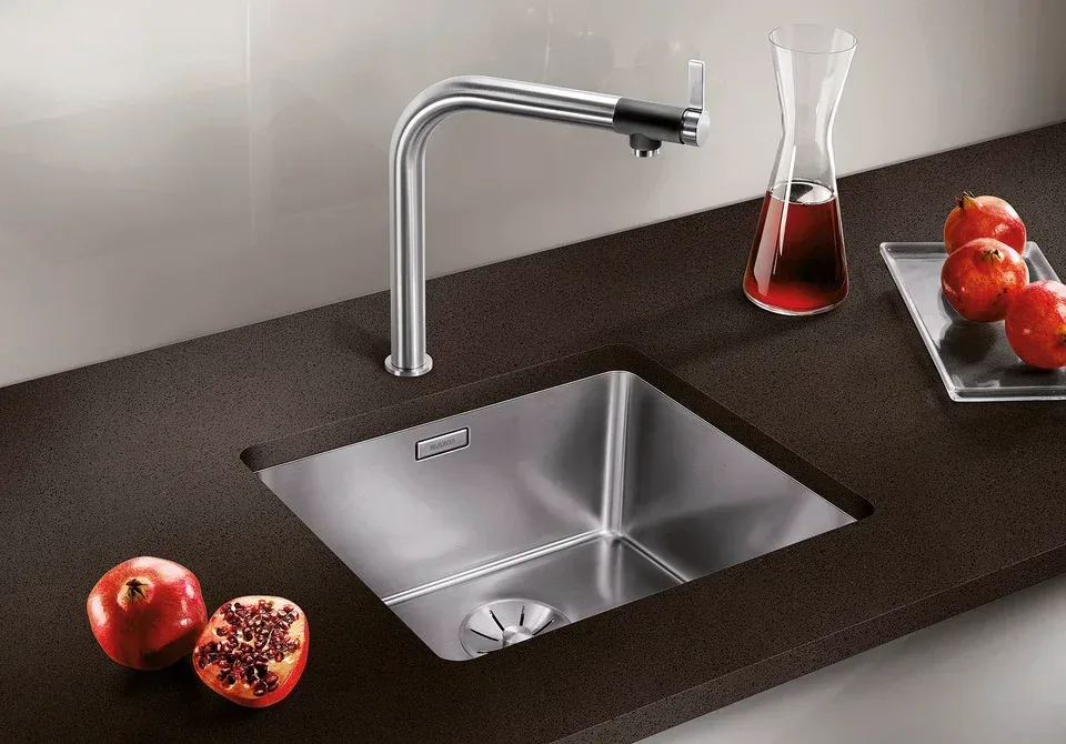 Évier Blanco inox encastré avec mitigeur, entouré de grenades sur plan de travail foncé