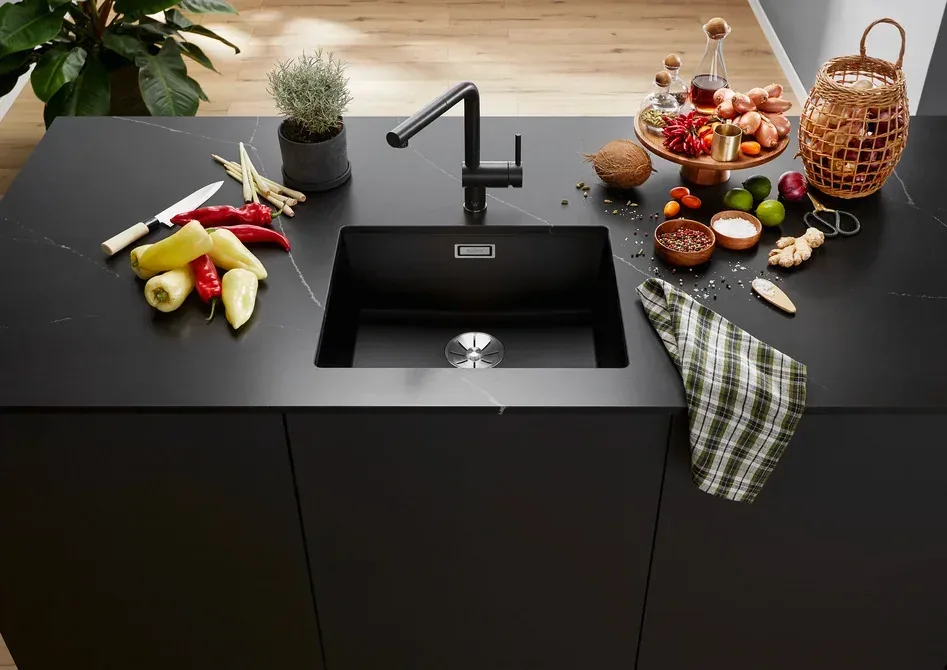 Évier de cuisine noir en granit avec mitigeur noir mat sur plan de travail effet marbre