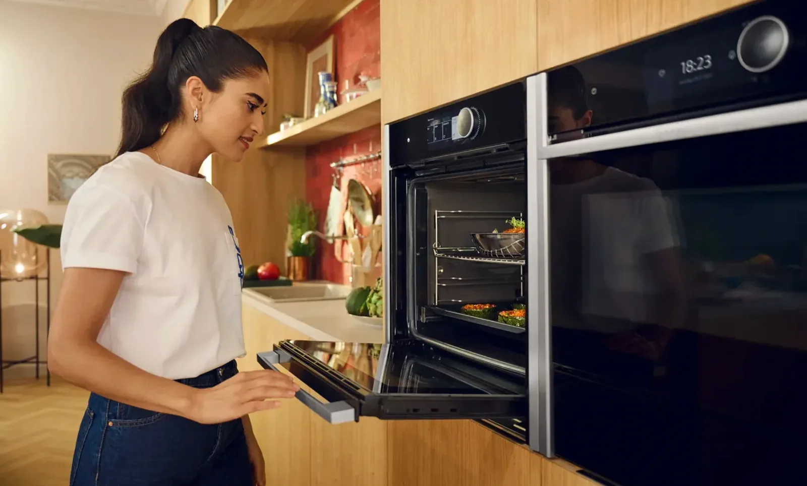 Four Neff encastrable avec écran digital dans une cuisine équipée bois et rouge