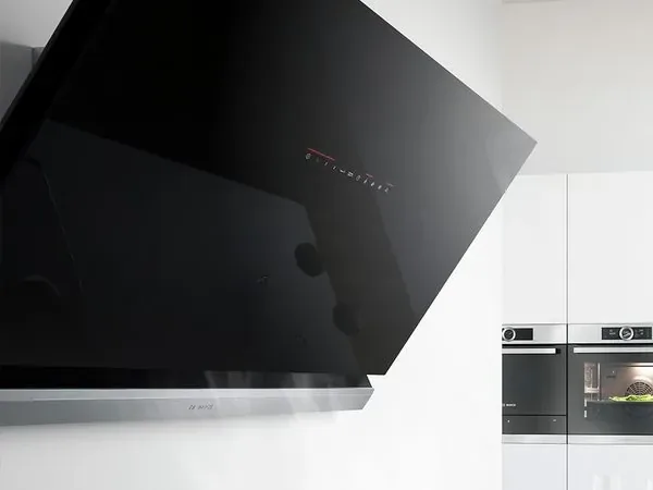 Hotte murale design noire inclinée dans une cuisine équipée blanche