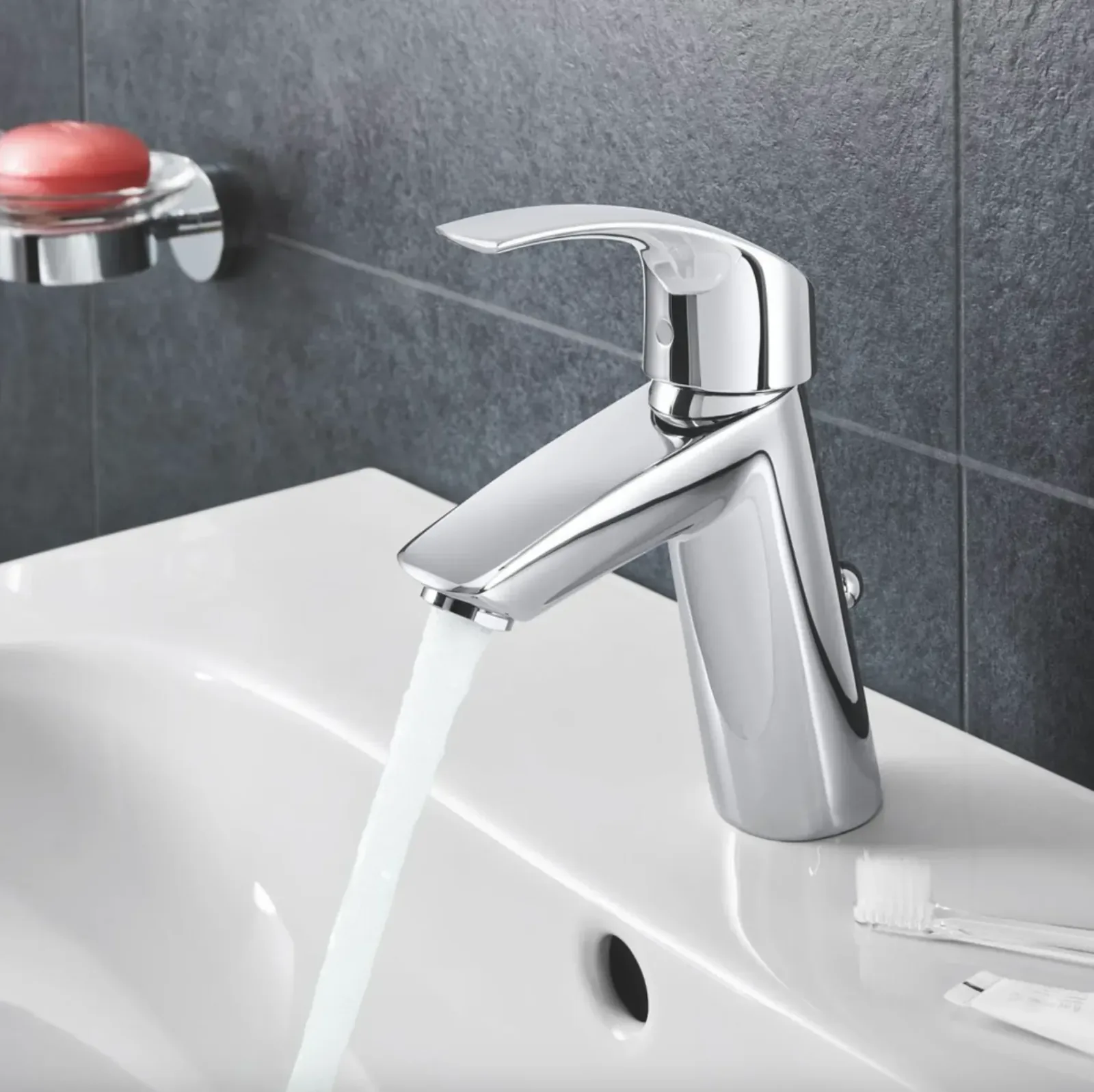 Mitigeur chromé de lavabo avec eau qui coule, sur vasque blanche en salle de bain