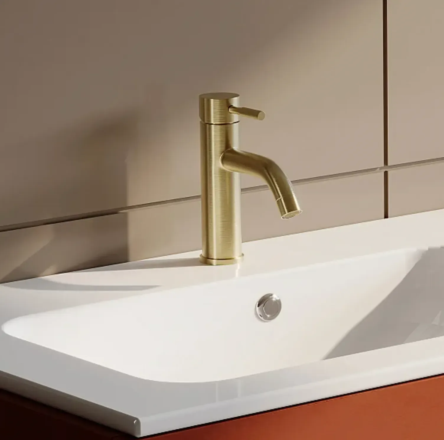 Mitigeur de lavabo laiton brossé doré sur vasque blanche en salle de bain