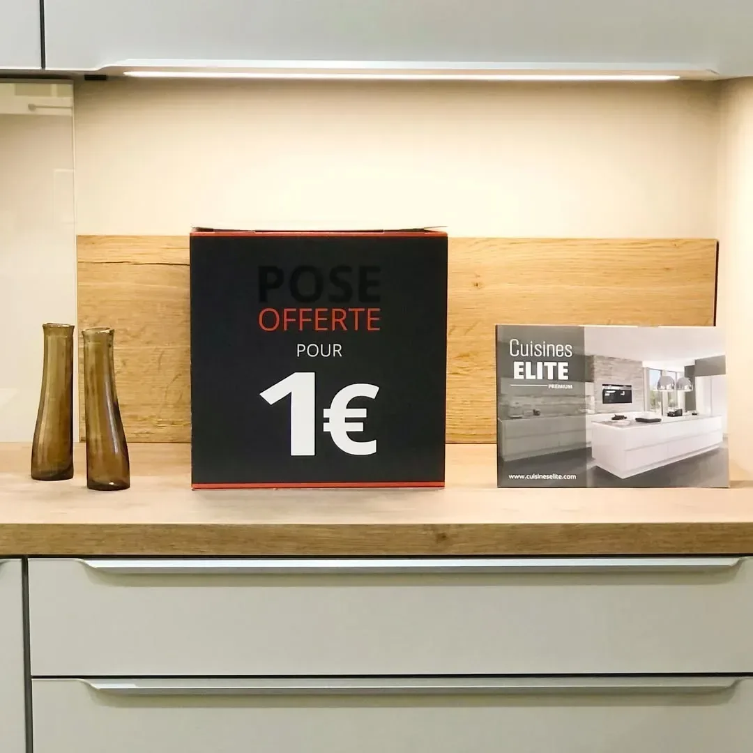 Affiche "Pose offerte pour 1€" et brochure Cuisines ELITE Premium sur plan de travail bois