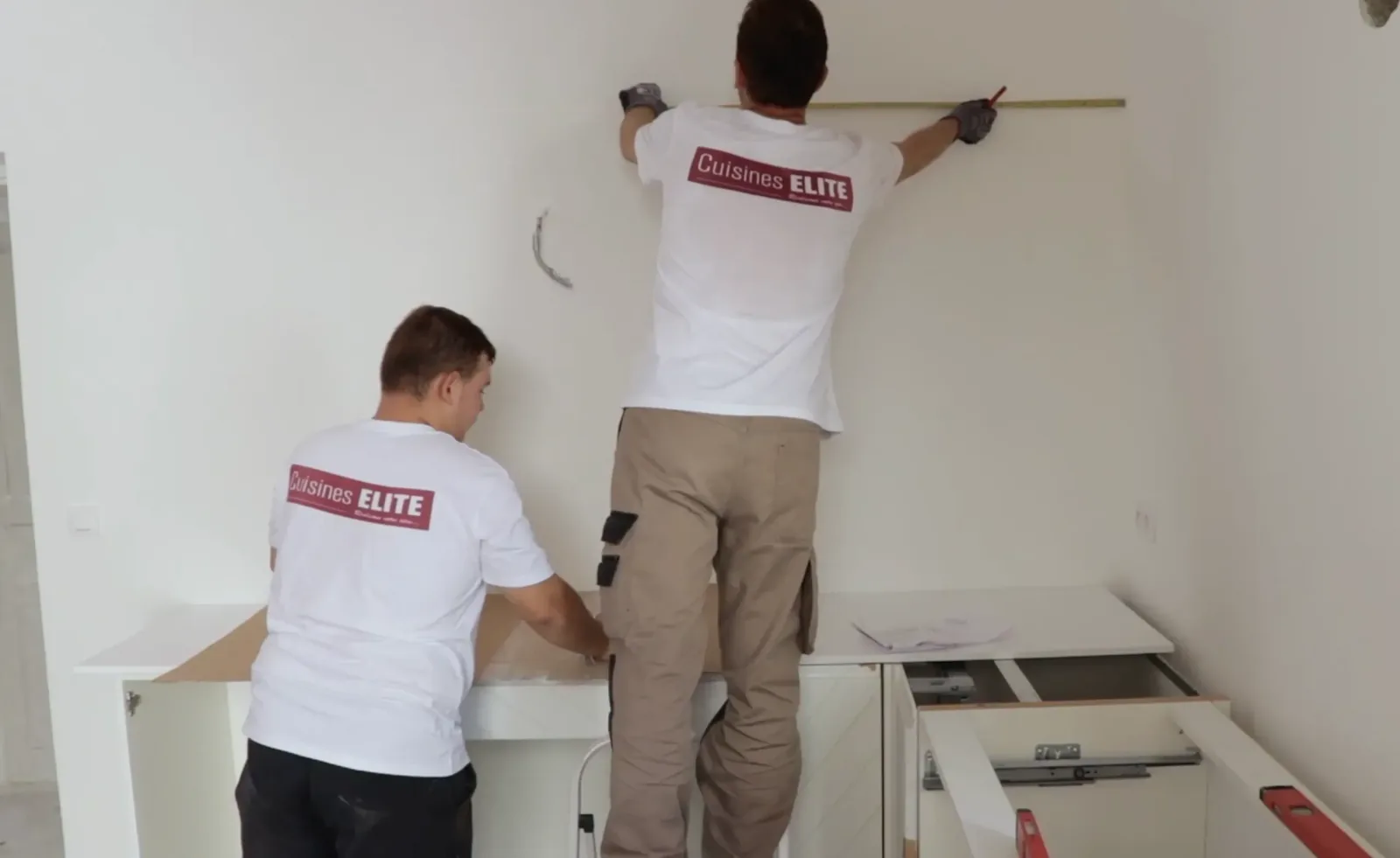 Poseurs Cuisines ELITE prenant des mesures au mur avant installation de meubles de cuisine