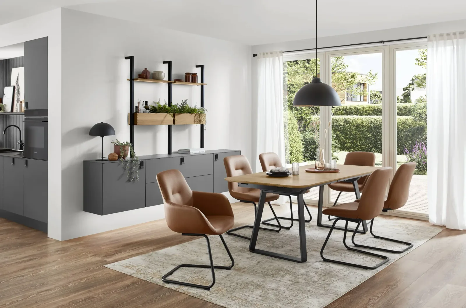Salle à manger ouverte sur cuisine avec table en bois, chaises en cuir camel et suspension noire