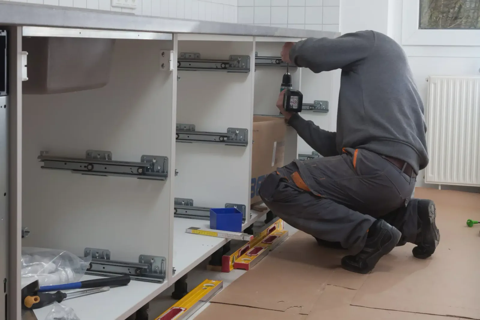 Technicien Cuisines ELITE montant les meubles bas d’une cuisine avec niveau à bulle