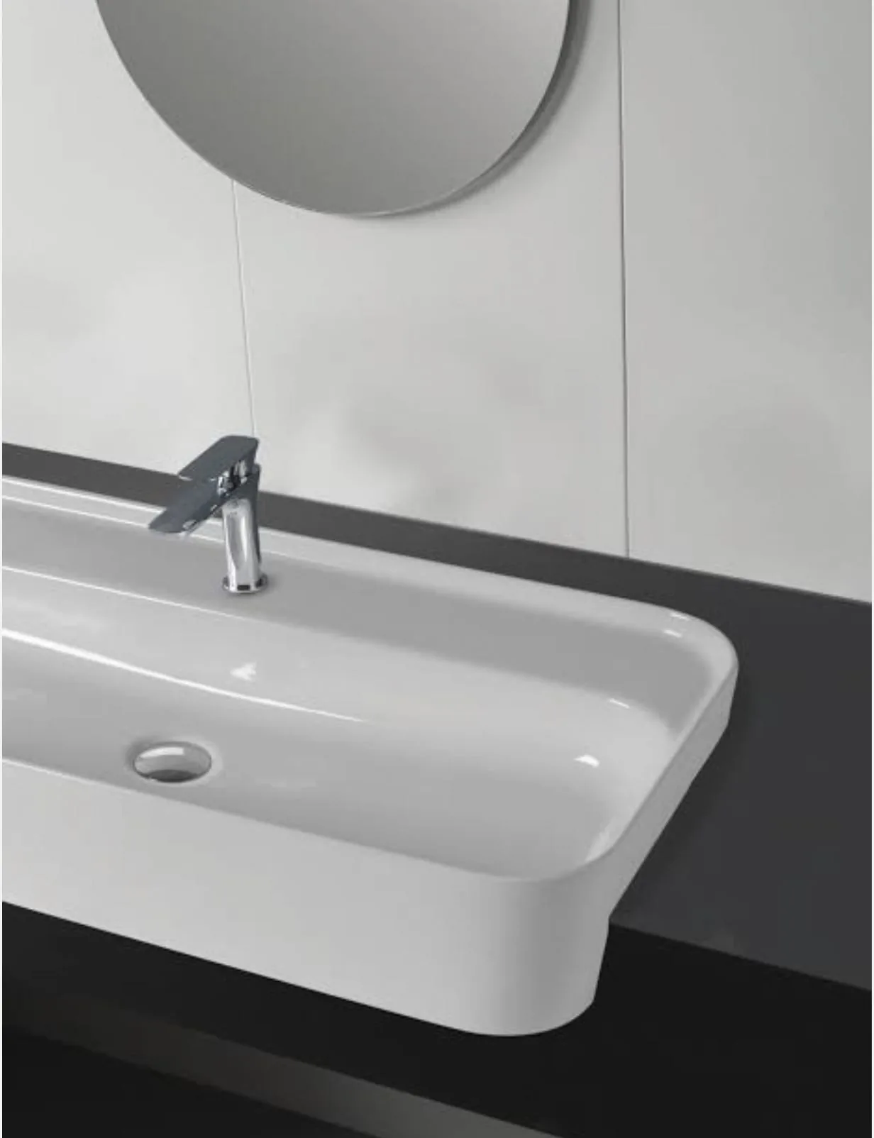 Vasque semi encastrée blanche rectangulaire avec mitigeur chromé sous un miroir rond
